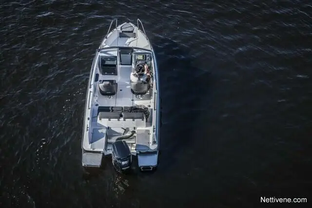 Aerial view of a motorboat on dark water, featuring two seats and a fishing rod holder, with a person at the helm.